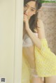 A woman in a yellow lingerie leaning against a wall.